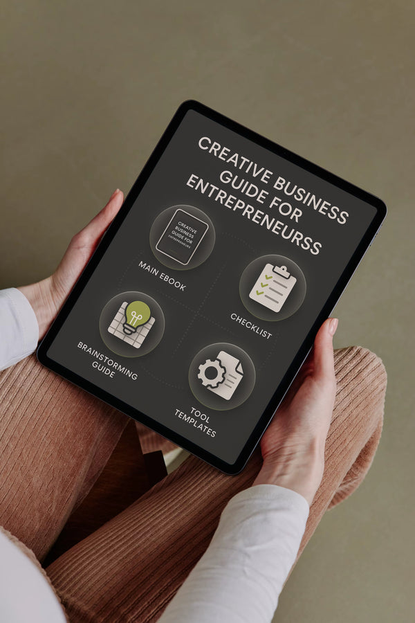 Person holding a tablet with 'Creative Business Guide for Entrepreneurs' on the screen.